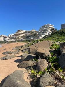a group of rocks on a beach with buildings at Beachfront apartment in Ballito! Casablanca in Ballito
