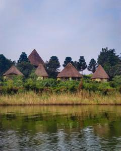 a group of huts on the shore of a body of water at Paradise Eco-Hub in Kabale