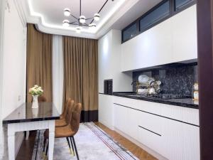 撒馬爾罕的住宿－Modern Lux，厨房配有白色橱柜和桌椅