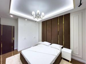 um quarto com uma grande cama branca e um lustre em Modern Lux em Samarcanda