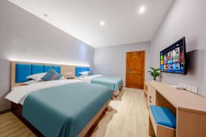 a bedroom with two beds and a flat screen tv at Mando Hotel - Kunming Changshui International Airport in Kunming
