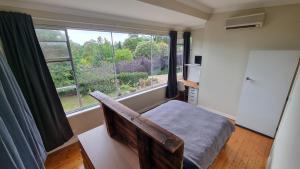 a bedroom with a bed and a large window at Architects Summer House, Mt Lofty Gardens in Crafers