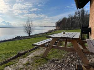 a wooden picnic table sitting next to a lake at Cottage with Seaview in Holbæk