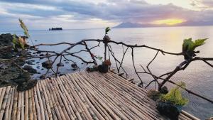 a bird perched on top of a wooden fence near the water at Bamboo house for Relaxation in Catbalogan