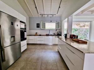 a large kitchen with white cabinets and appliances at Villa Mahogany confort, spacieuse in Le François