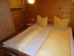 ein großes Bett in einer Holzhütte mit zwei Kissen in der Unterkunft Bauernhof Sinnersberg in Kitzbühel