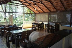 uma sala de jantar com mesas, cadeiras e janelas em Silver springs Homestay Chickmagalur em Chikmagalur