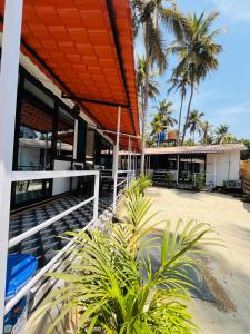 a house on the beach with palm trees at LAKSHDEEP COTTAGES in Canacona