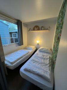 two beds in a small room with a window at Chalet vakantiepark Kleine Belties 18 in Hardenberg