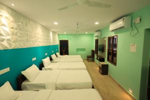 a row of beds in a room with green walls at Kailasaa Residency in Tiruvannāmalai