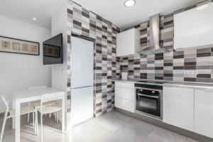 a kitchen with white cabinets and a table and a stove at Placid Puerto in Puerto de Sagunto +25 photos