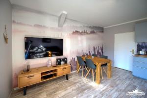 una sala da pranzo con un tavolo e una TV a parete di Auszeit-im-Harz Haus 1 Wohnung Schnarcherklippe a Schierke