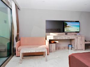 a living room with a couch and a tv at Delta Hotels By Marriott Bodrum in Yalıkavak