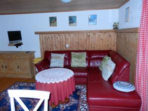 een woonkamer met een rode leren bank en een tafel bij Ferienhaus La Valletta in Rueras
