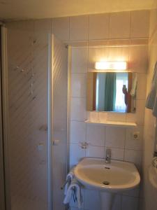 Baño blanco con lavabo y espejo en Gasthaus Hingerl en Obing