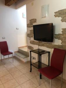 ein Wohnzimmer mit 2 Stühlen und einem Flachbild-TV in der Unterkunft Casa nonna Tetta fronte mare 4 letti in Livorno