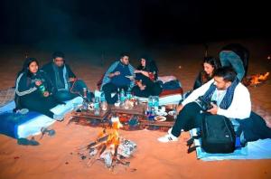 Sam dunes desert safari camp في جيلسامر: مجموعة من الناس يجلسون حول النار