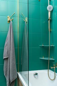 a green bathroom with a tub and a shower at Cozy Old Town Studio in Krakow