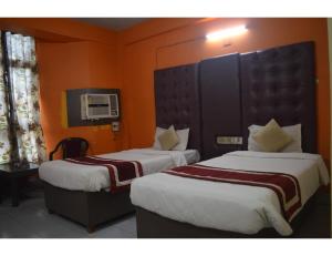 Duas camas num quarto com paredes cor de laranja em Hotel Aadhar, Barbil, Odisha em Bada Barabīl