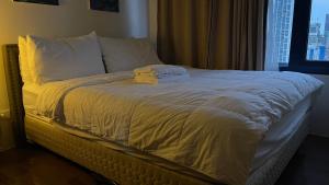 1 cama con sábanas y almohadas blancas y ventana en Destina @Air Residences Makati, Metro Manila, en Manila