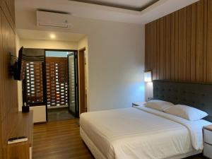 a bedroom with a large white bed and a balcony at Urbanview Hotel Nardis Living near UMY in Ngabean