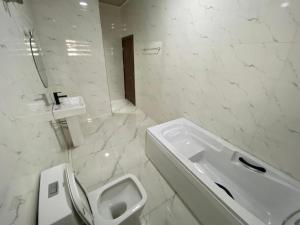 a white bathroom with a toilet and a sink at MOK Apartments & Suites in Lagos