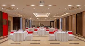 a banquet hall with white tables and red chairs at Hotel Saket 27 in New Delhi