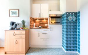 a kitchen with white cabinets and a blue tile wall at Traumblick-2 in Utersum