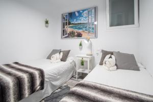 2 camas en una habitación con paredes blancas en Apartamento Arco de los Blanco, en Cádiz