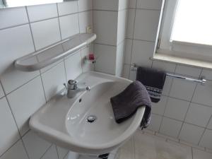 un lavandino bianco in bagno con asciugamano di Ferienwohnung Metzler a Poppenhausen