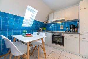 a kitchen with a white table and chairs and blue tiles at Traumblick-4-Meerblick in Hedehusum