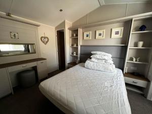a bedroom with a bed with white sheets and pillows at Beautiful Caravan With Decking At Azure Seas Ref 32060az in Lowestoft