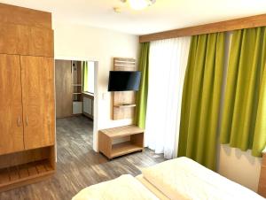 Berghotel Glockenberg في سانكت أندرياسبرغ: غرفة نوم بسرير وستارة خضراء