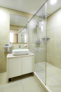 ein Bad mit einem Waschbecken und einer Glasdusche in der Unterkunft HIGHVIL APARTAMENTS in Astana
