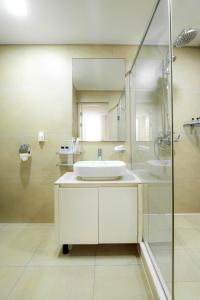 a white bathroom with a sink and a shower at HIGHVIL APARTAMENTS in Astana