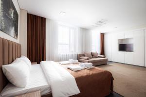 um quarto de hotel com uma cama e um sofá em HIGHVIL APARTAMENTS em Astana
