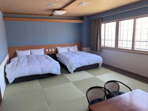 1 dormitorio con 2 camas, mesa y sillas en Kojohama Onsen Hotel, en Shiraoi