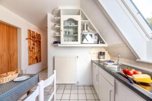 een zolderkeuken met witte kasten en een wastafel bij widj-loft in Oldsum