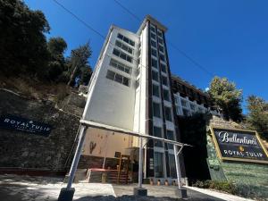 a tall building with a sign in front of it at Royal Tulip Luxury Hotel, Kufri, Shimla in Shimla