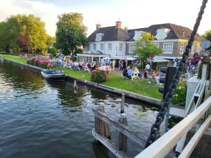 a group of people sitting on the grass by the water at De Nederlanden, Restaurant & Boutique Hotel in Vreeland