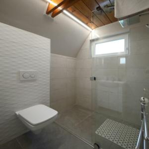 uma casa de banho branca com um WC e um chuveiro em Horizont idéző ParkMotel em Orfű