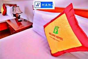 Cette chambre comprend un lit avec un oreiller jaune et rouge. dans l'établissement Bao Long Hotel, à Hô-Chi-Minh-Ville