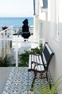 a bench on a balcony with the ocean in the background at Boulders Beach Hotel, Cafe and Curio shop in Simonʼs Town