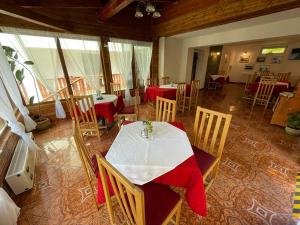 une salle à manger avec une table, des chaises et un tissu rouge dans l'établissement Pensiunea Olt Centrum/ Olt Centrum panzió, à Băile Tuşnad