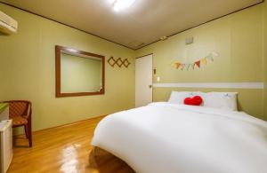 a bedroom with a large white bed and a mirror at J Motel in Yeosu