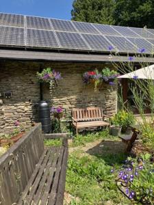 a garden with a bench and a building with solar panels at Yr Ysgubor Converted milking parlour in Llandysul