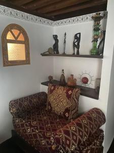 una sala de estar con sofá y algunos estantes en Charmant Ryad à 1mn de BAB BOUJLOUD DAR SERRAJ, en Fez