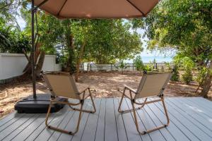 two chairs sitting on a deck under an umbrella at Brand New Beachfront & Secluded Tiny House in Koh Samui 