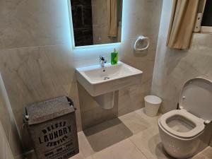 W łazience znajduje się umywalka, toaleta i lustro. w obiekcie Luxury Waterfront Apartment w mieście Mellieħa