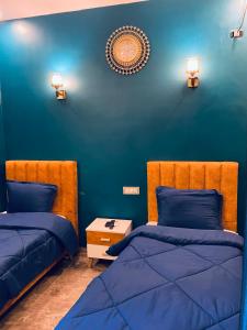 1 dormitorio con 2 camas y pared azul en Hotel Dar Ali, en Túnez